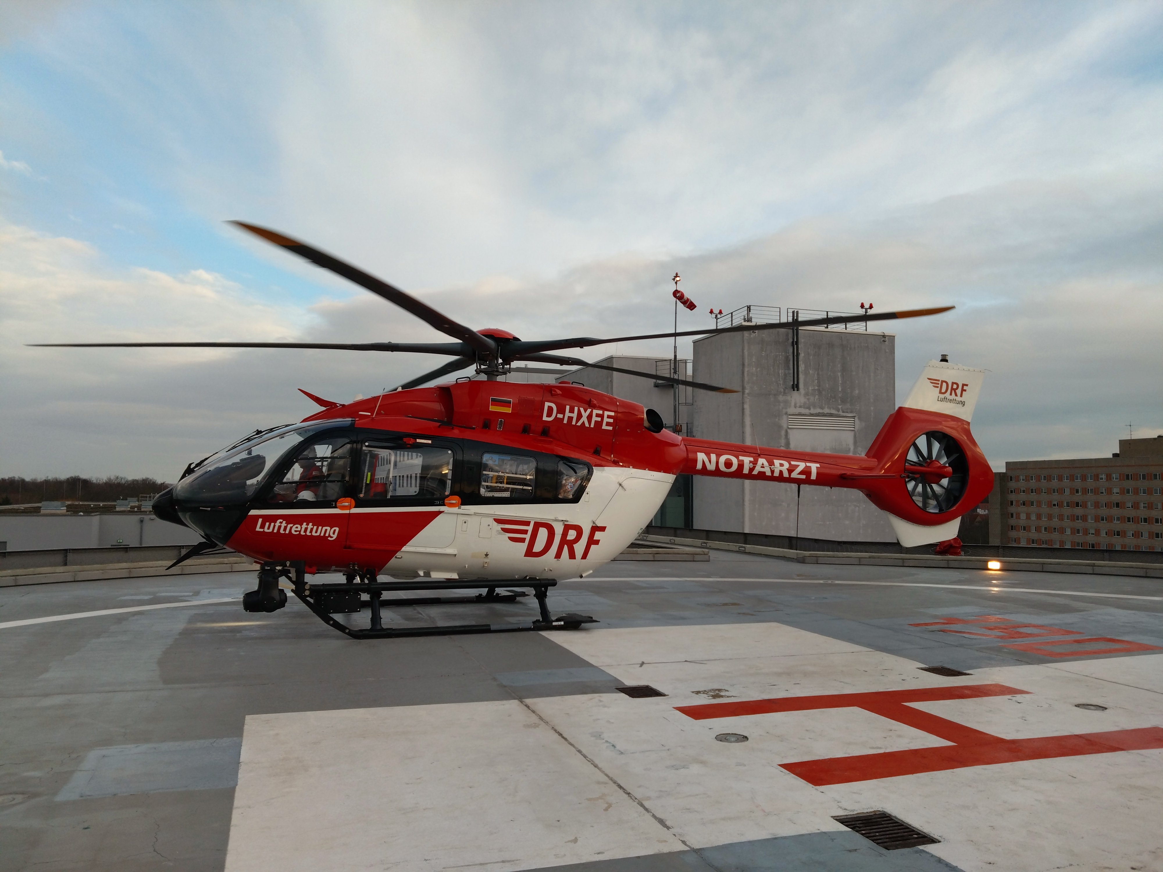 Ein rot-weißer Rettungshubschrauber steht auf dem Dachlandeplatz eines Klinikums