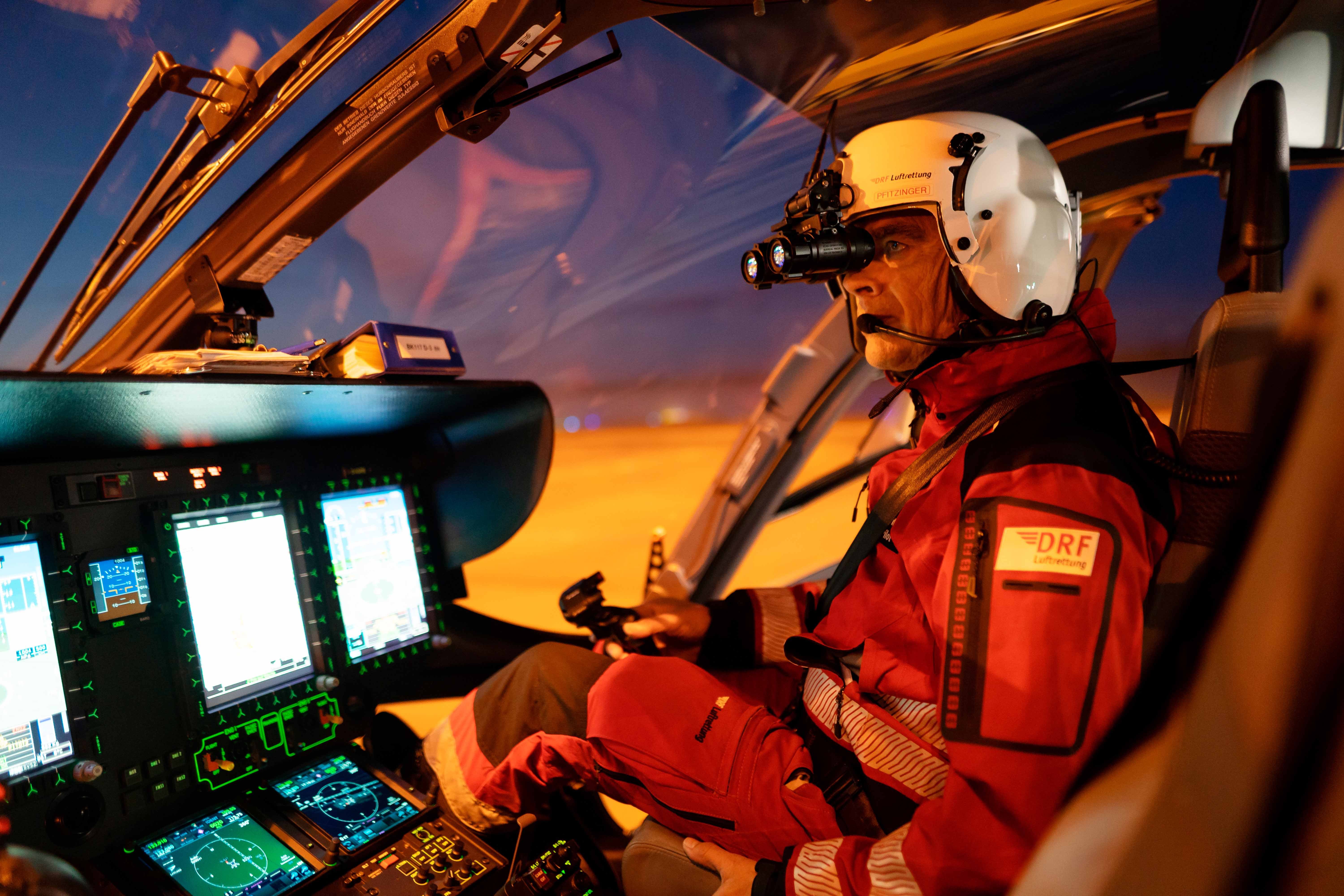 Ein Hubschrauberpilot sitzt bei Dunkelheit mit Nachtsichtbrille im Cockpit