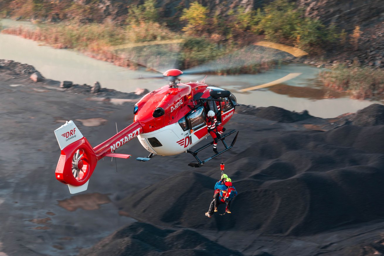 Ein Winchvorgang wird an einem rot-weißen Hubschrauber durchgeführt